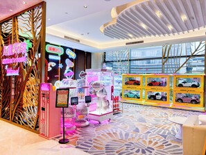 A children's play area with arcade games, a neon sign, and a patterned floor.