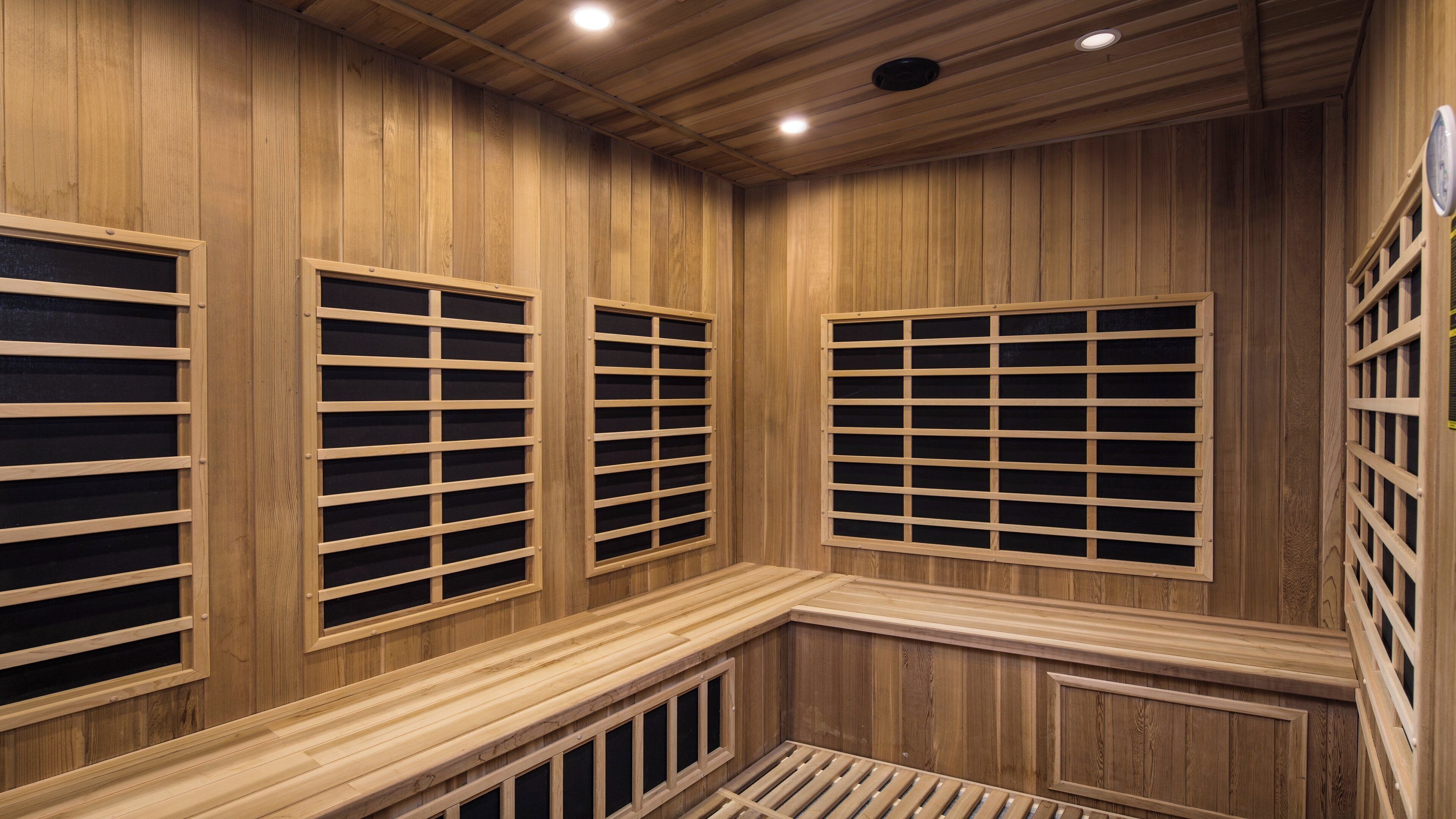 A sauna room with wooden walls, a bench, and a window with a grid pattern.