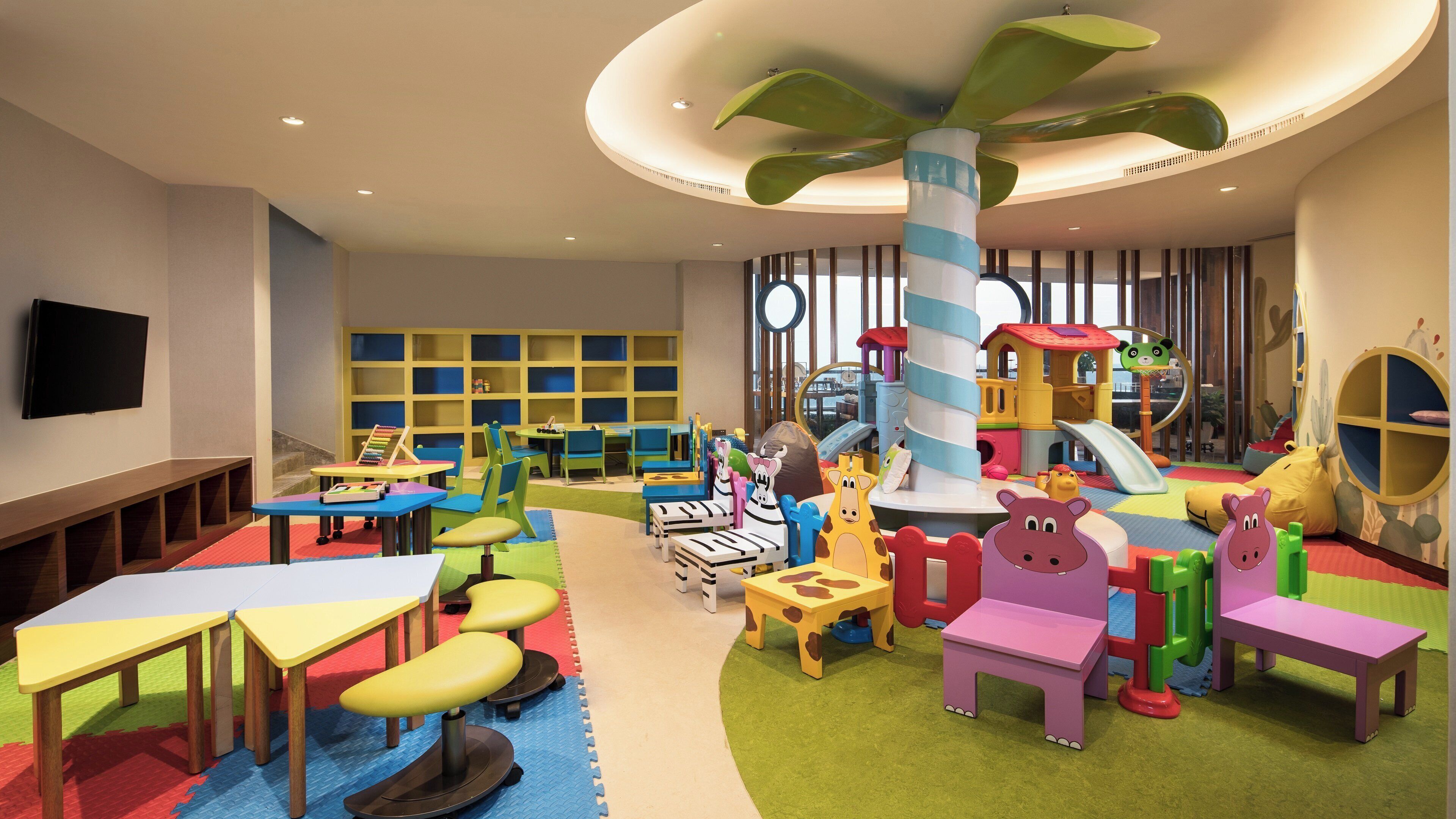 Un área de juegos infantiles con mesas, sillas y un parque infantil.