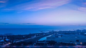 A coastal town at dusk with a prominent road leading to the sea, a bridge, and a mix of residential and commercial buildings. - Holiday Inn Suzhou Taihu Lake by IHG (Suzhou)