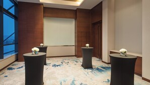 A conference room with a large screen, three black tables with white flowers, and a patterned carpet. - Holiday Inn Suzhou Taihu Lake by IHG (Suzhou)