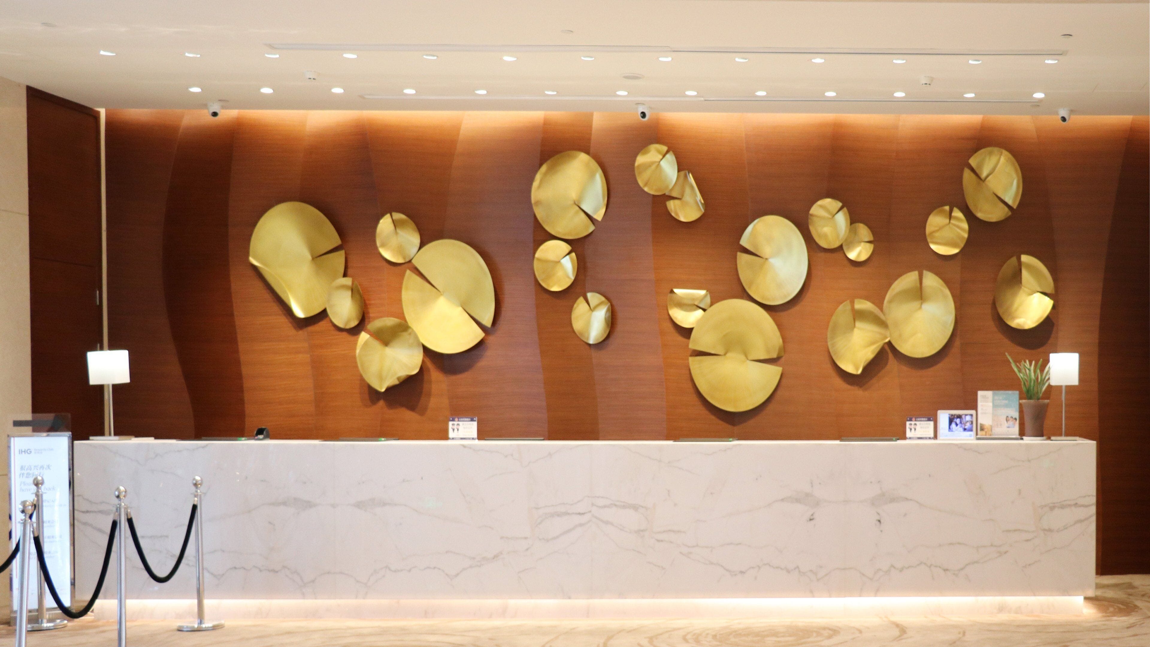 A reception desk with a marble top, a wooden wall with circular wall art, and a security camera.