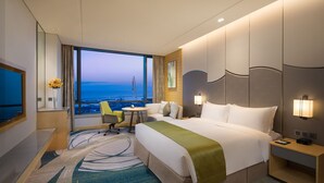 A hotel room with a large bed, a desk, a chair, a small table, and a view of the ocean. - Holiday Inn Suzhou Taihu Lake by IHG (Suzhou)