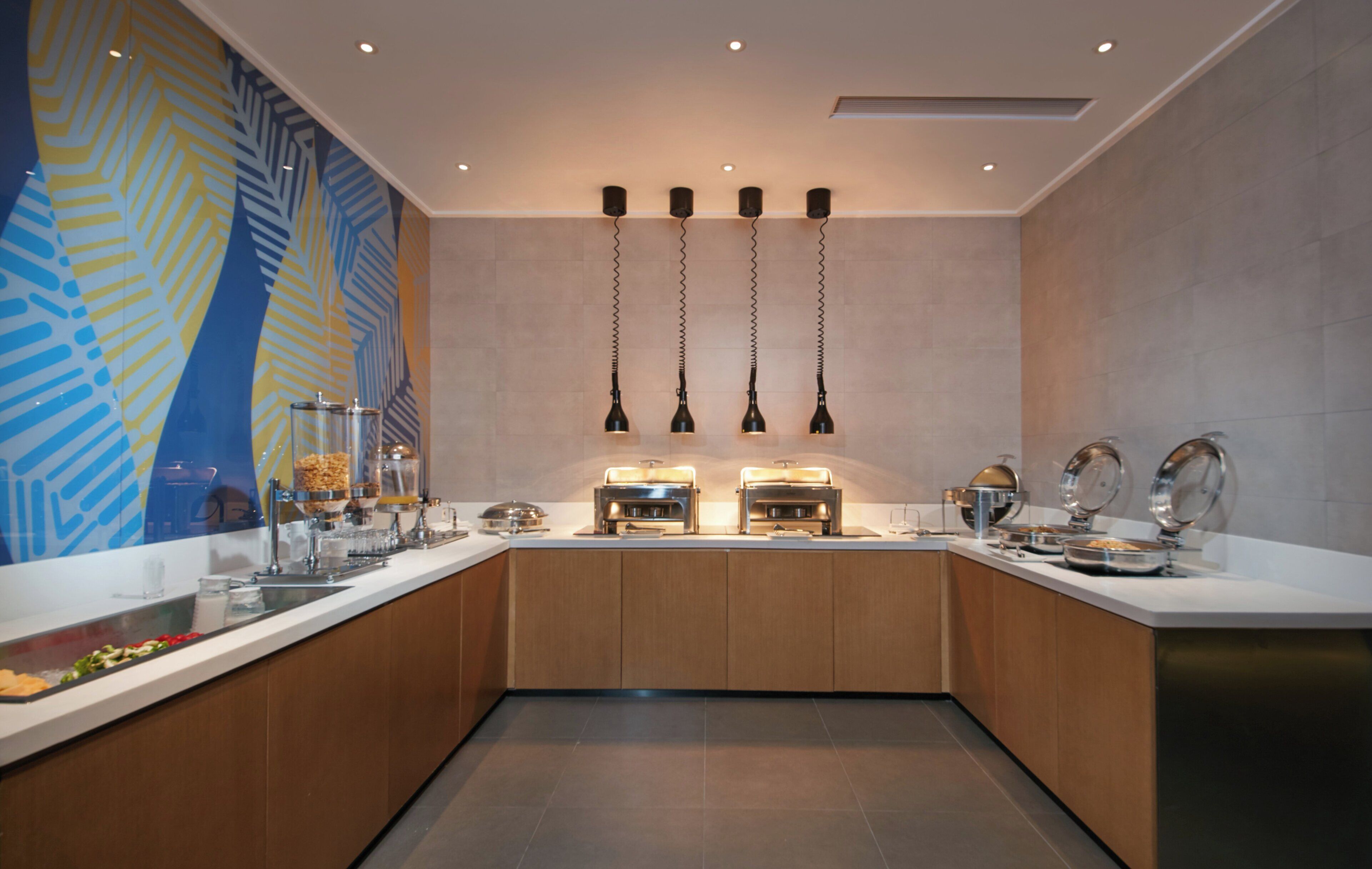 A modern kitchen with a central island, overhead pendant lights, and a decorative wall mural.