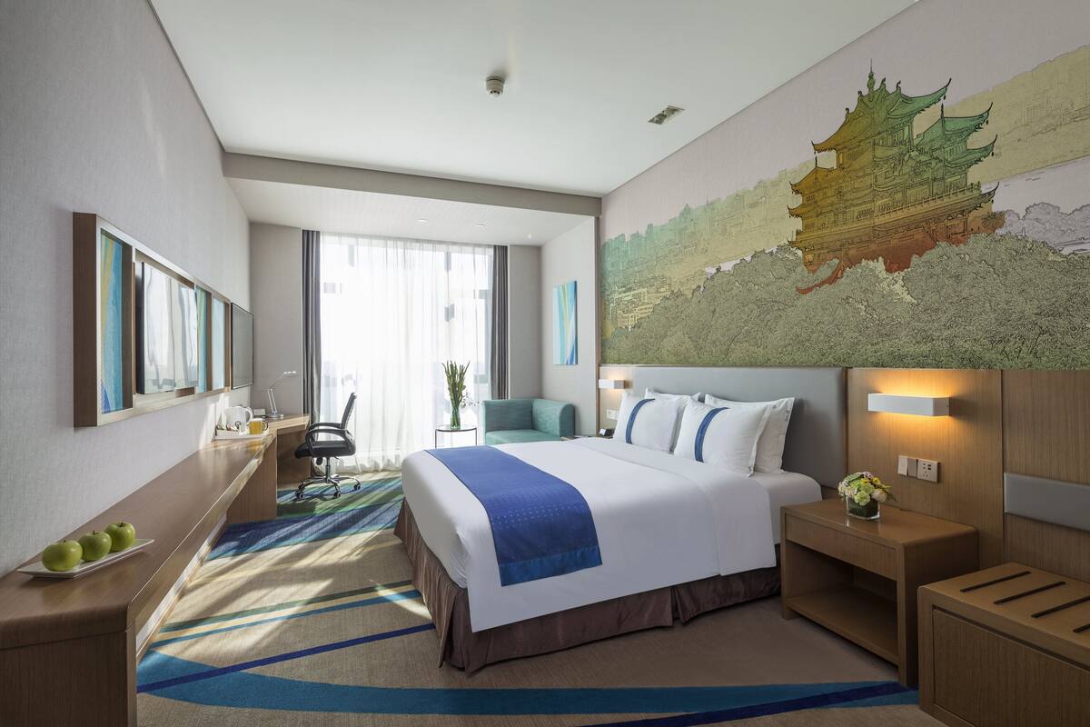 Une chambre d’hôtel avec un grand lit, un bureau, une chaise et une carte accrochée au mur.