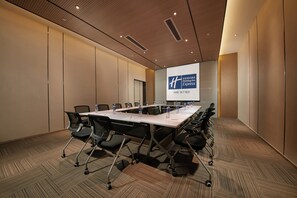A conference room with a long table, chairs, and a projector screen displaying a hotel name. - Holiday Inn Express Hangzhou East Station by IHG (Hangzhou)