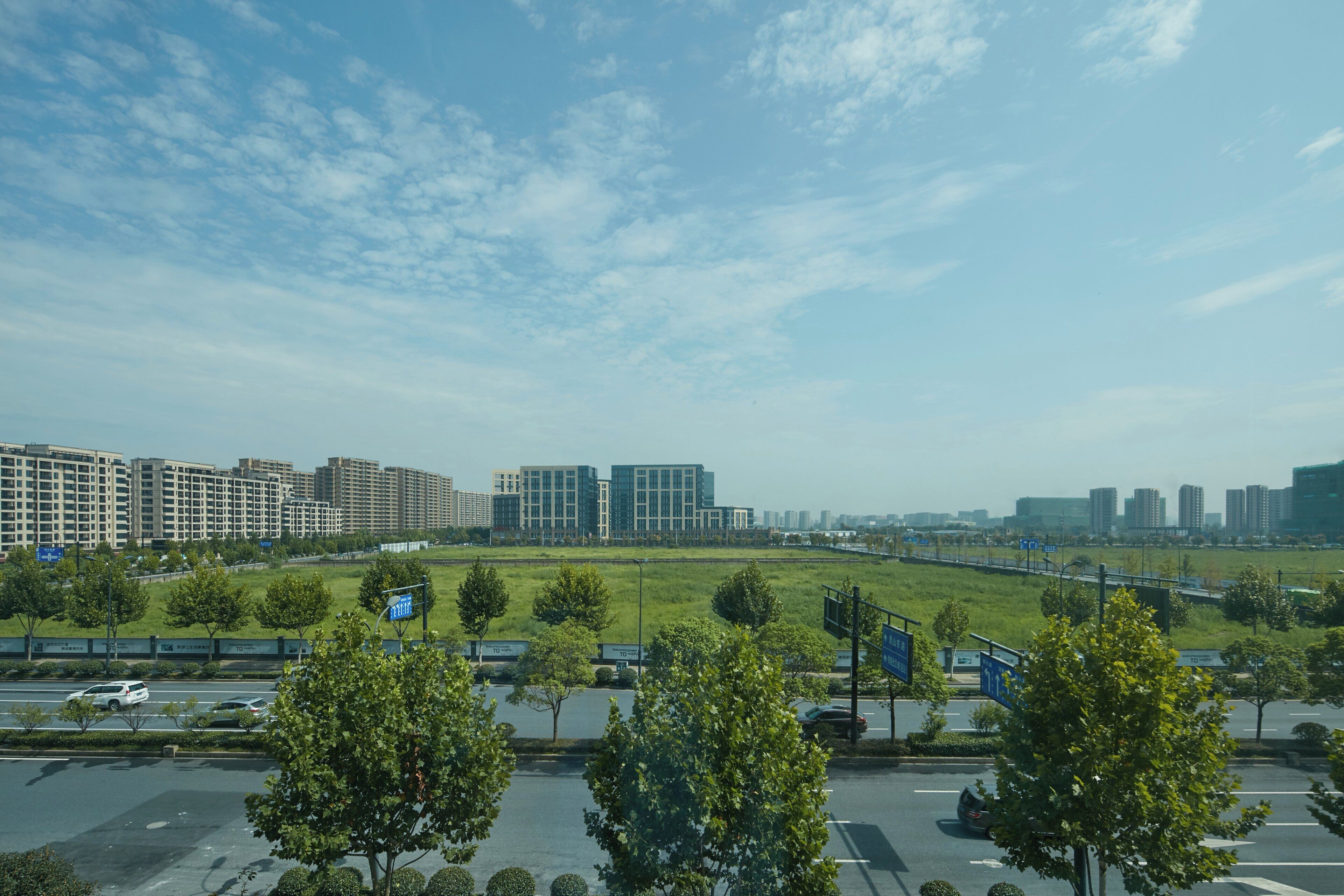 Een parkeerplaats met bomen en een uitzicht op moderne gebouwen op de achtergrond.