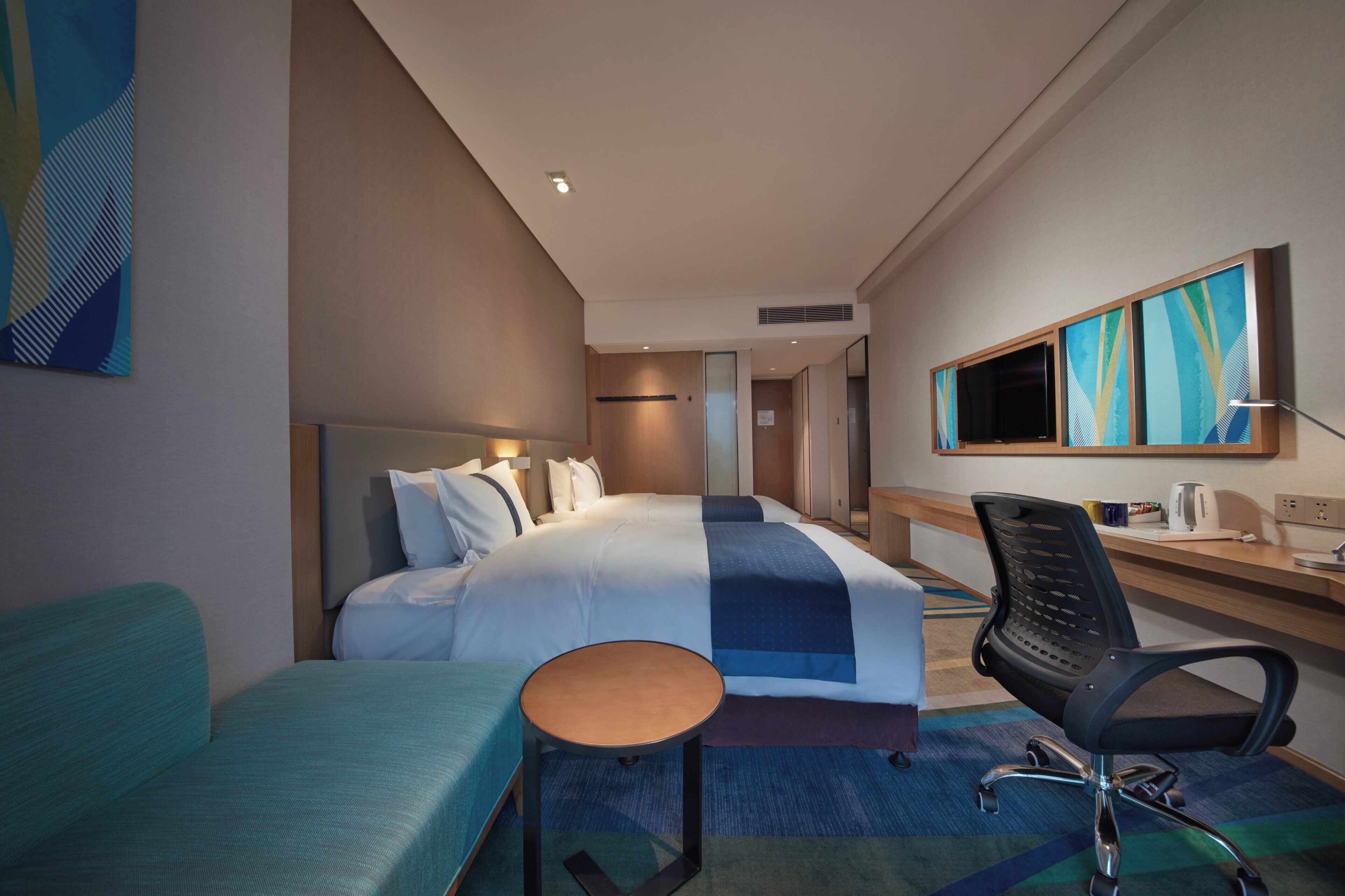 Ein Hotelzimmer mit Bett, Schreibtisch, Stuhl und Fernseher.