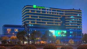 A multi-story hotel with a prominent 'Holiday Inn Express' sign, large windows, and a modern architectural design. - Holiday Inn Express Hangzhou East Station by IHG (Hangzhou)