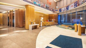 A modern hotel lobby with a reception desk, a seating area, and a large window offering a view of the outside. - Holiday Inn Express Hangzhou East Station by IHG (Hangzhou)