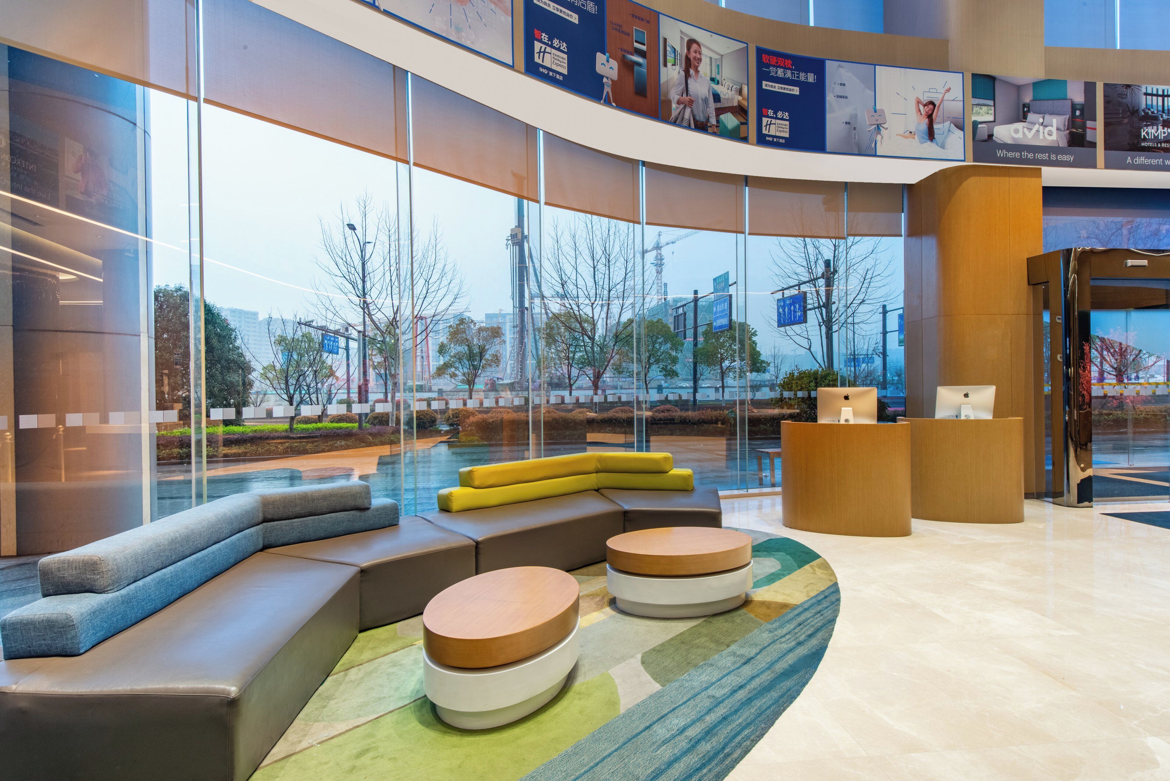 A modern lobby with seating areas, a reception desk, and large windows offering views of the outside.
