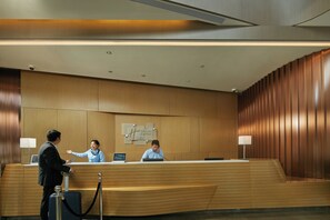 A hotel reception desk with a wooden finish, a digital screen, and a security camera. - Holiday Inn Express Hangzhou East Station by IHG (Hangzhou)
