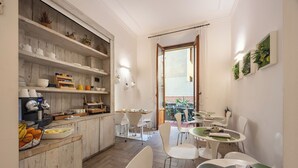 A modern kitchen with white cabinetry, a dining area with white chairs, and a view of the outdoor patio. - Eco Urban B&B (Florence)