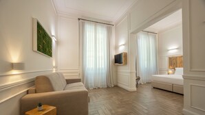 A modern hotel room with a sofa, a TV, a bed, and a green wall decoration. - Eco Urban B&B (Florence)