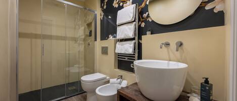Un baño moderno con cabina de ducha de vidrio, un lavamanos grande y un inodoro.