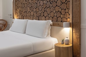 A bed with white bedding, a wooden headboard with logs, a bedside table with a lamp, and a small plant. - Eco Urban B&B (Florence)