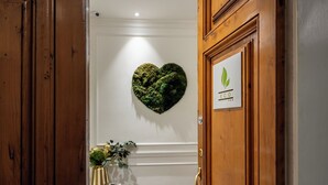 A wooden door with a sign, a heart-shaped wall decoration, and a small table with a plant. - Eco Urban B&B (Florence)