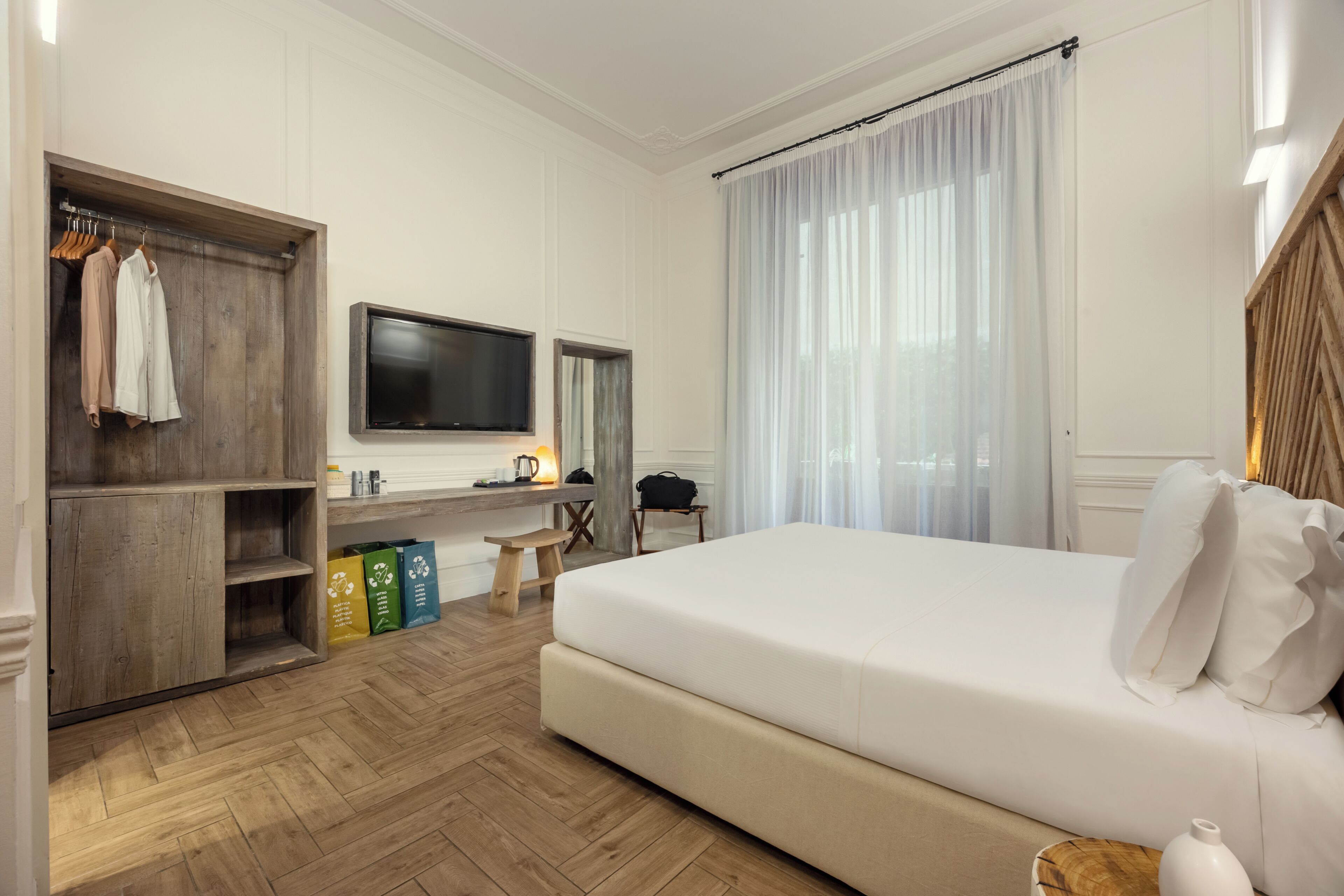 A hotel room with a bed, a TV, a desk, and a wardrobe.