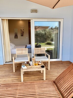 Een kamer met een bed, een eettafel met stoelen en een schuifdeur naar een tuin.