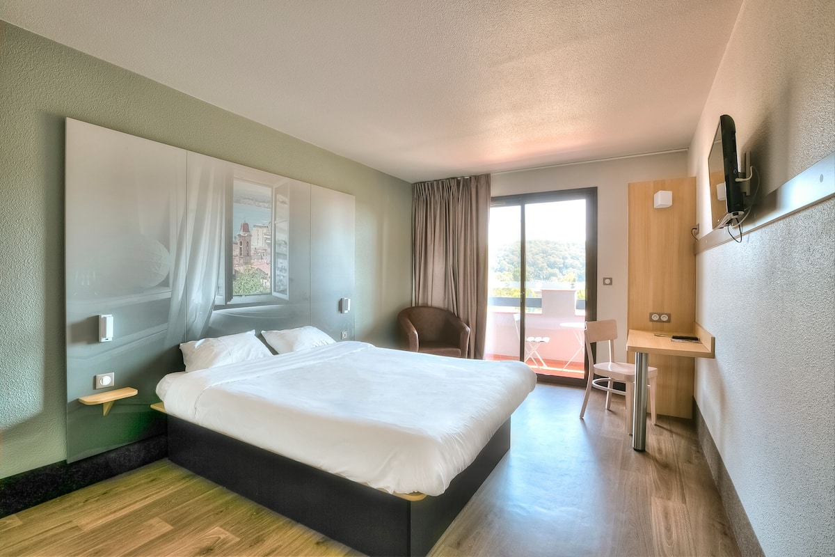 Una habitación de hotel moderna con una cama grande, un escritorio y una silla.