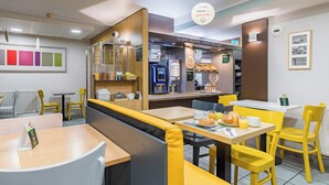 A modern café with yellow and white seating, a coffee machine, and a menu board. - B&B Hotel Tours Sud Joué-lès-tours (Joue-les-Tours)