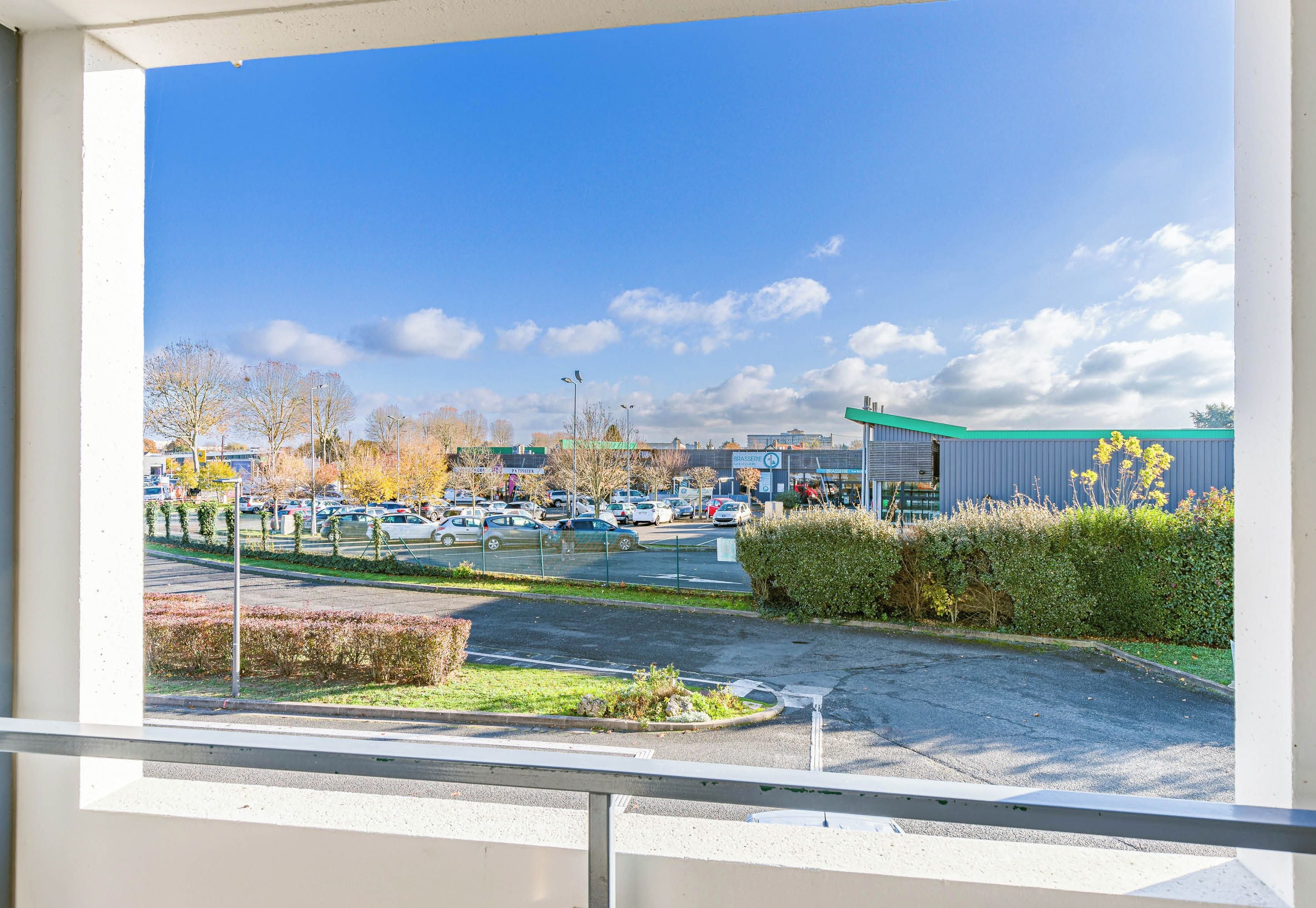 A parking lot with cars, a building with a green roof, and a clear blue sky.