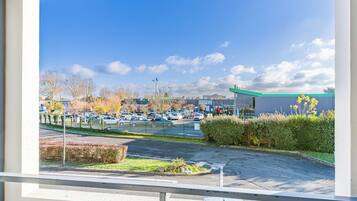A parking lot with cars, a building with a green roof, and a clear blue sky.