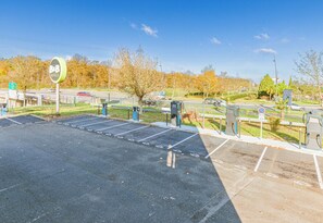 Ein Parkplatz mit markierten Stellplätzen, ein Schild für ein 4-Sterne-Hotel und ein klarer, blauer Himmel.