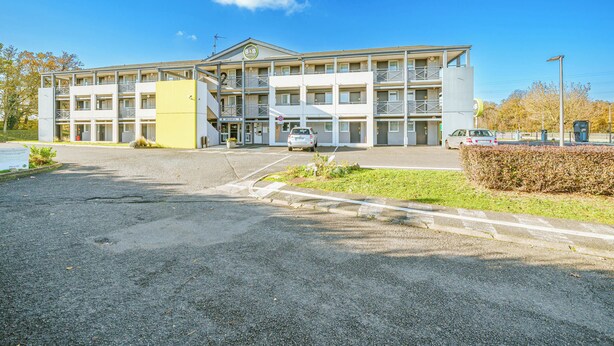 A multi-story hotel with a central entrance, balconies, and a parking area. - B&B Hotel Tours Sud Joué-lès-tours (Joue-les-Tours)
