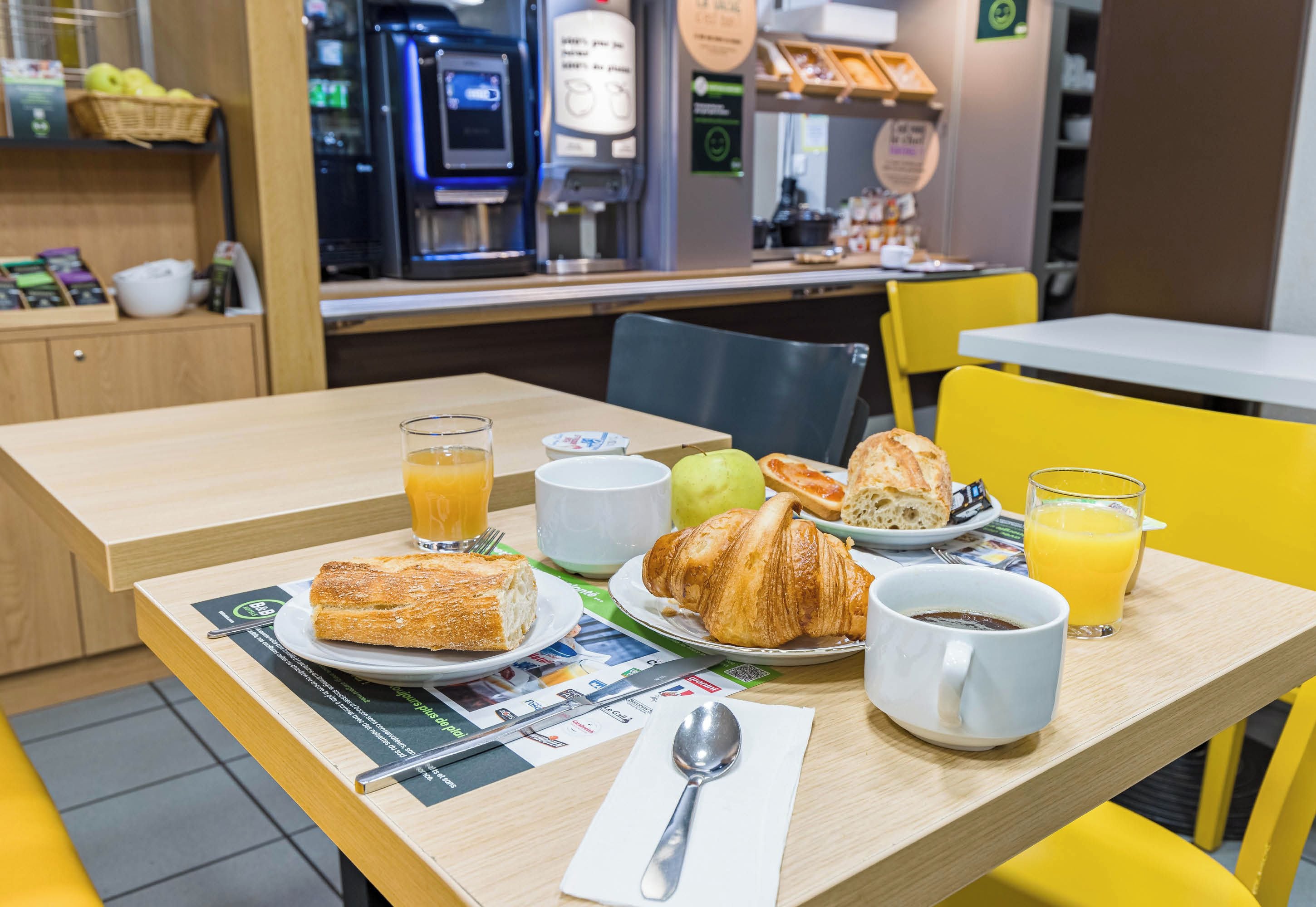 A breakfast table with croissants, juice, and coffee.