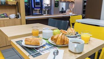A breakfast table with croissants, juice, and coffee.