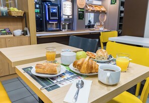 Una mesa de desayuno con cruasanes, jugo y café.