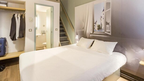 A hotel room with a bed, a wardrobe, a mirror, a bathroom, and a staircase. - B&B Hotel Tours Nord 1 Val De Loire (Tours)