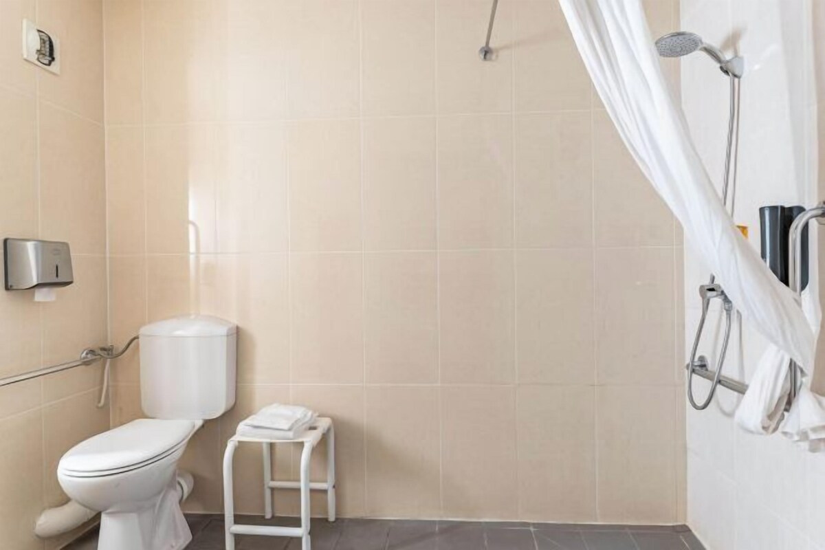 A bathroom with a toilet, a shower, a towel rack, and a hand dryer.