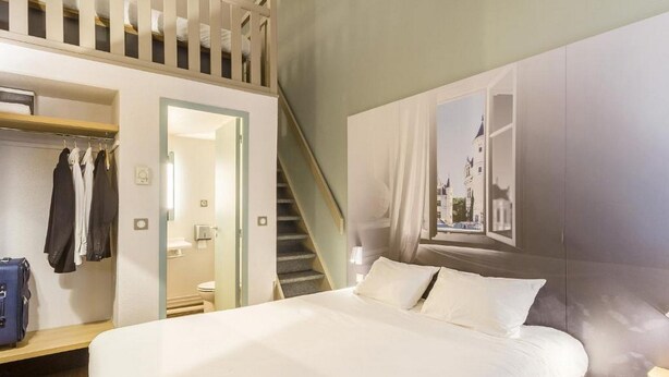 A hotel room with a bed, a wardrobe, a mirror, a bathroom, and a staircase. - B&B Hotel Tours Nord 1 Val De Loire (Tours)