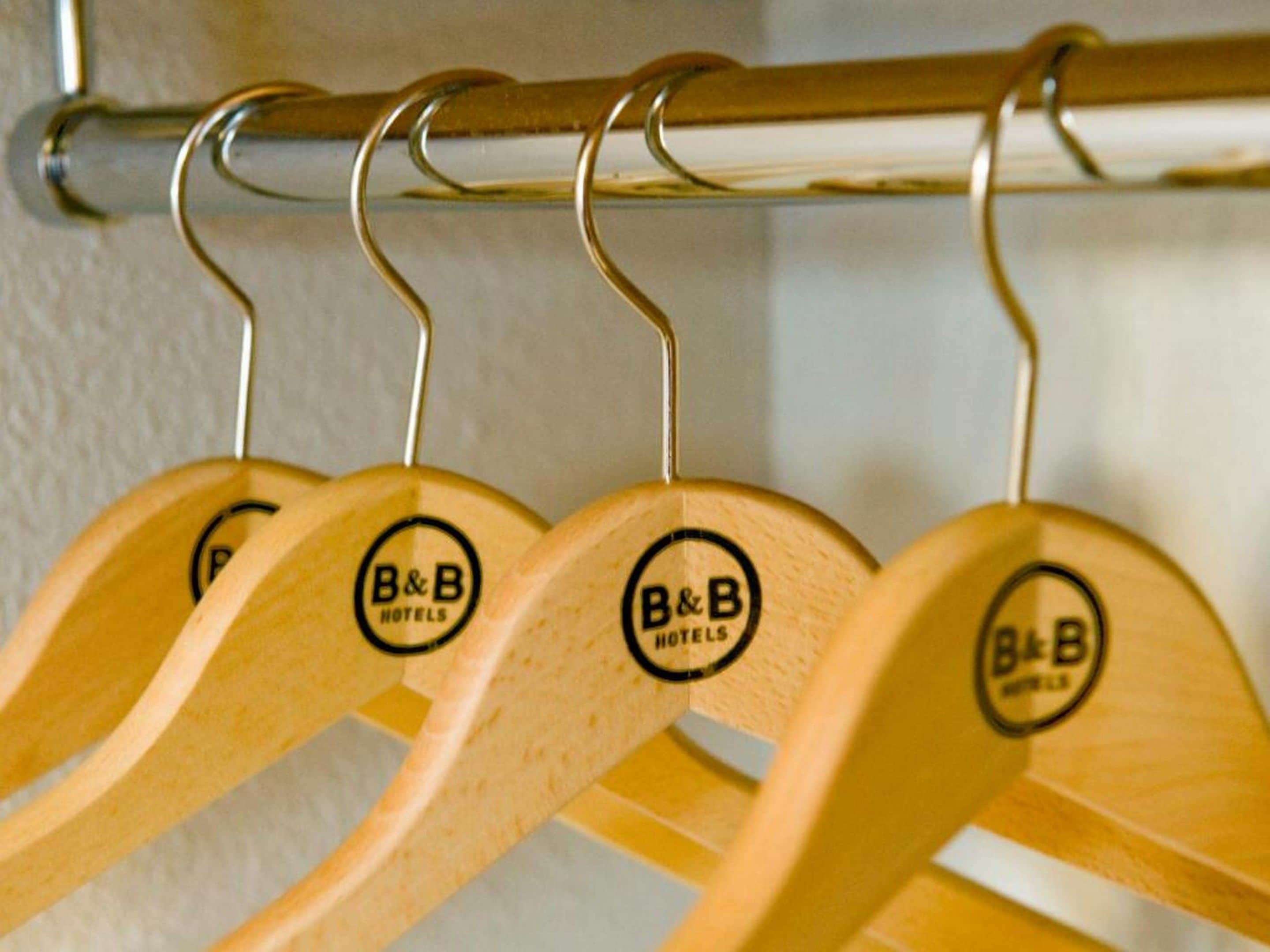 Een kledingrek met houten hangers en een logo met de tekst 'B&B HOTELS'.