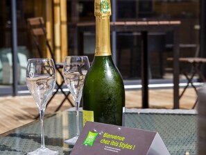 A bottle of champagne, two empty wine glasses, and a welcome sign on a table. - ibis styles Chalons en Champagne Centre (Chalons-en-Champagne)
