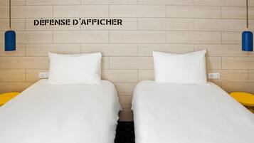 A hotel room with two beds, a wooden headboard, and a wall-mounted light fixture.