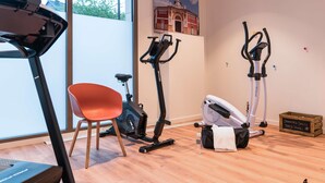 Una habitación con una caminadora, bicicletas estáticas, una silla roja y un caja de madera con la etiqueta 'SERVETTES SALES DIRTY TOWELS'.