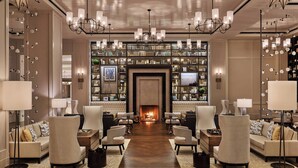 A spacious lobby with a central fireplace, comfortable seating, and a well-stocked bookshelf.