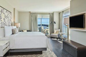 A hotel room with a large bed, a desk, a chair, a TV, and a view of the city. - The Hotel at Avalon, Autograph Collection (Alpharetta)