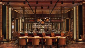 A bar area with wooden flooring, bar stools, and a central bar counter with bottles and glasses.