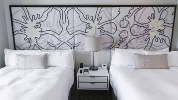 A hotel room with two beds, a nightstand with a lamp, a phone, and a small table.