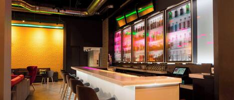 A bar area with a neon sign, bar stools, and a counter with a digital display.