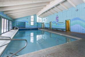 An indoor swimming pool with clear water, wooden walls, and a ceiling with beams. - Chateau Sans Nom 17 (Mammoth Lakes)
