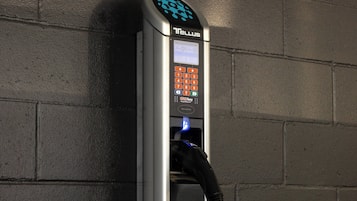 Estación de carga para vehículos eléctricos Tellus, con teclado y cable de carga conectado.