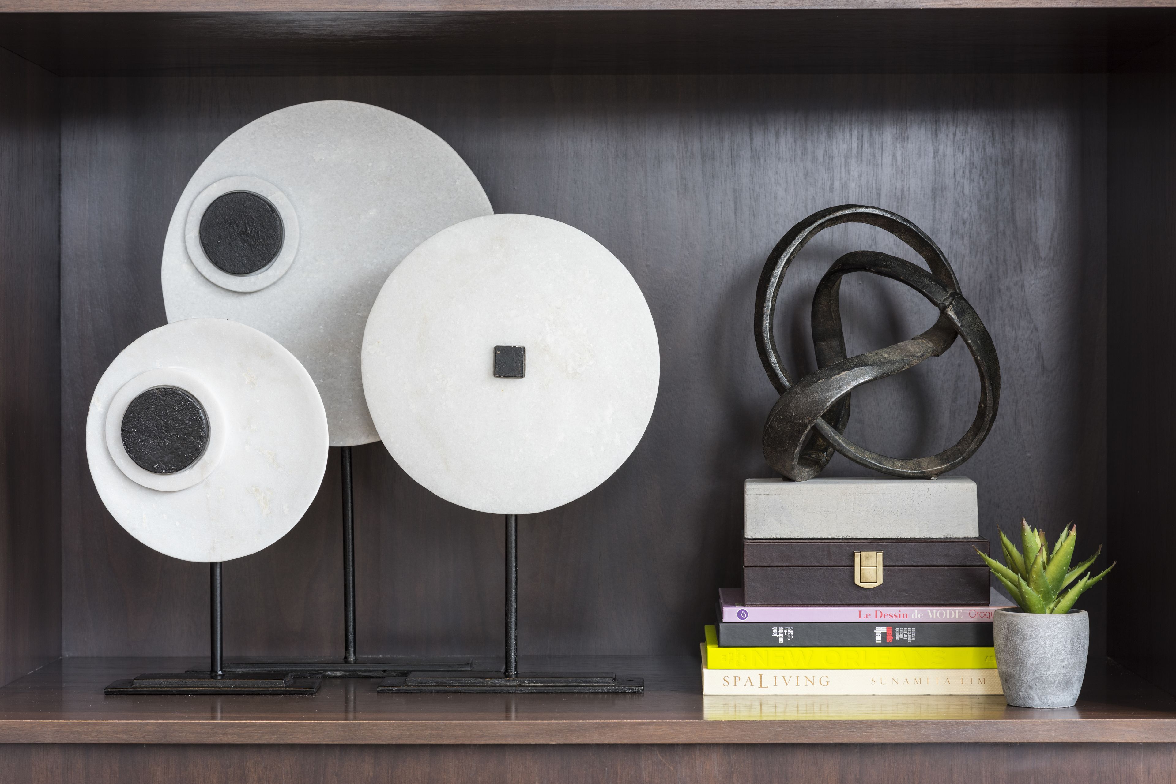 Een plank met decoratieve borden, een metalen sculptuur en een stapel boeken.