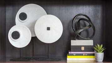 Een plank met decoratieve borden, een metalen sculptuur en een stapel boeken.