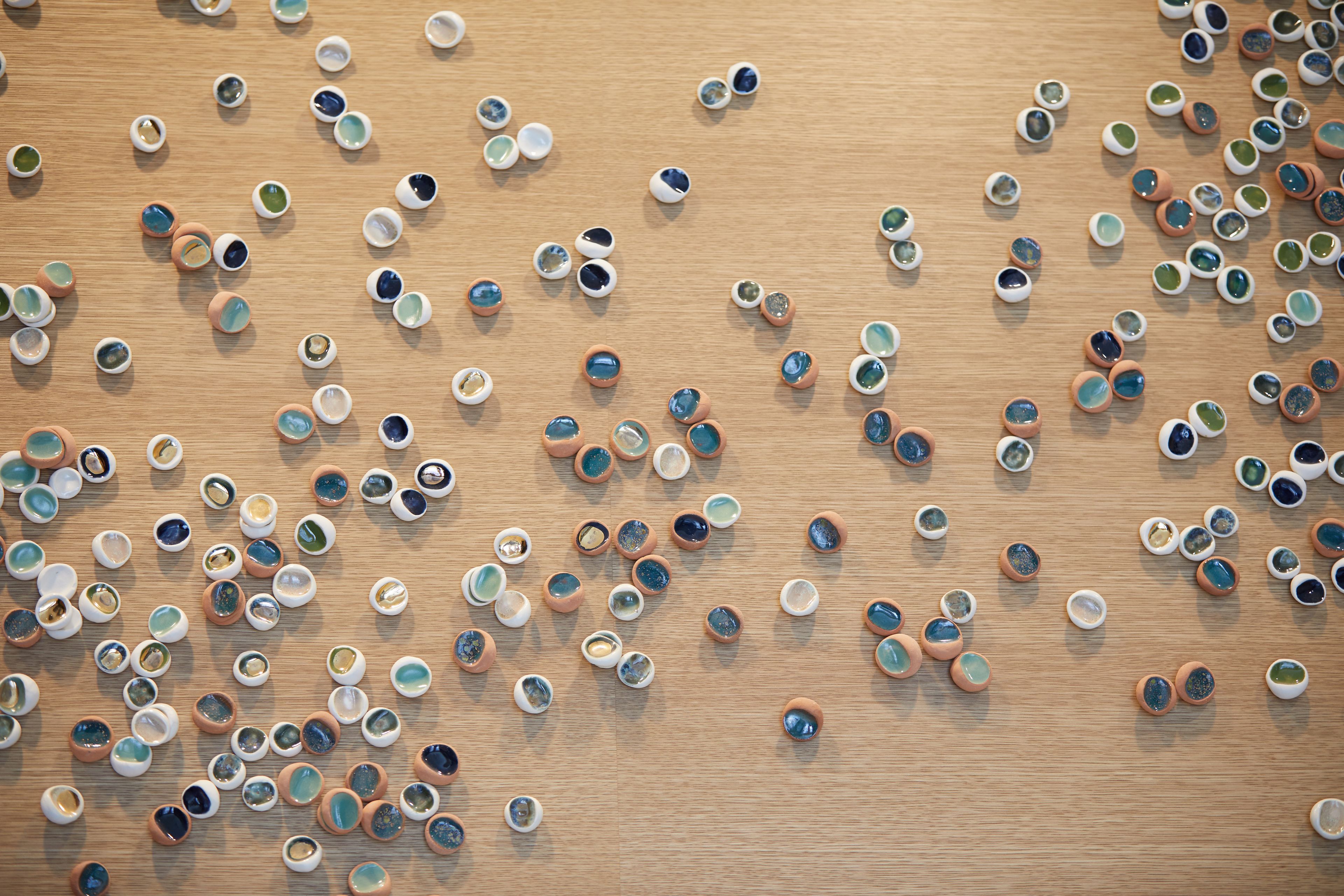 A wooden surface with numerous small, round, ceramic objects scattered across it.