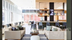 A modern lounge area with sofas, a coffee table, and a bar with various bottles.
